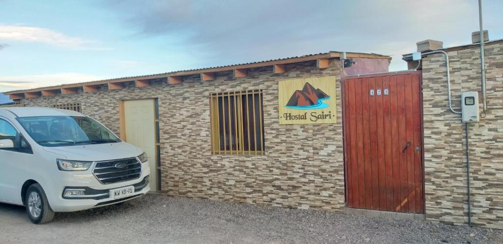 a white van parked in front of a brick building at HOSTAL SAIRI in San Pedro de Atacama