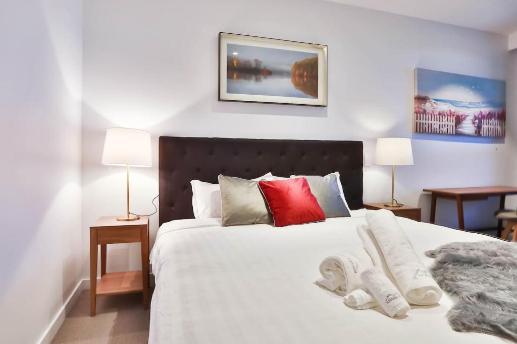 a bedroom with a large white bed with two lamps at Box Hill Central Sky One Apartment in Box Hill