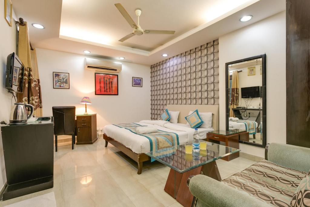 - une chambre avec un lit, une table et un canapé dans l'établissement The Hermitage By Cosy Hotels near Lajpat Nagar, Delhi, à New Delhi