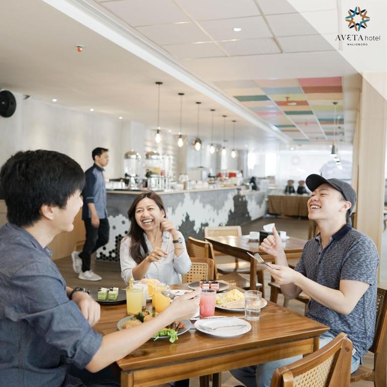 a group of people sitting around a table in a restaurant at Aveta Hotel Malioboro in Yogyakarta