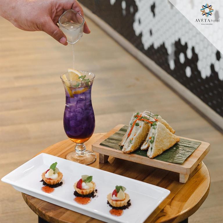 a person pouring a drink into a plate of food at Aveta Hotel Malioboro in Yogyakarta