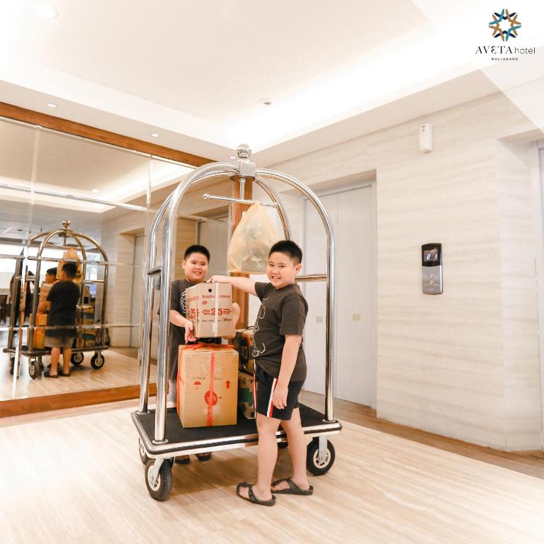 two young boys standing next to a cart with luggage at Aveta Hotel Malioboro in Yogyakarta
