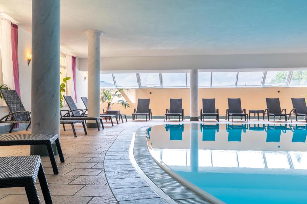 uma piscina do hotel com cadeiras e mesas em Hotel Asterbel em Braies