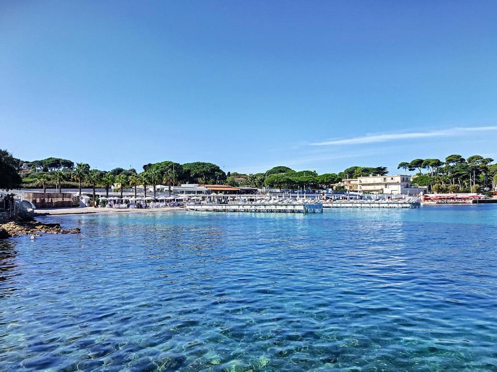 a large body of water with a beach and boats at Hotel Miramar- Cap d'Antibes - La Garoupe plage in Antibes