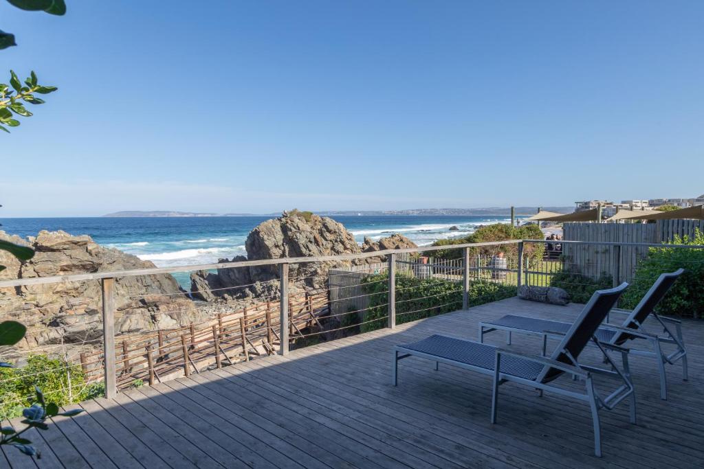 古爾博姆斯特蘭德的住宿－Picnic Rock Seaside Accommodation，海滩上带两把椅子和长凳的甲板