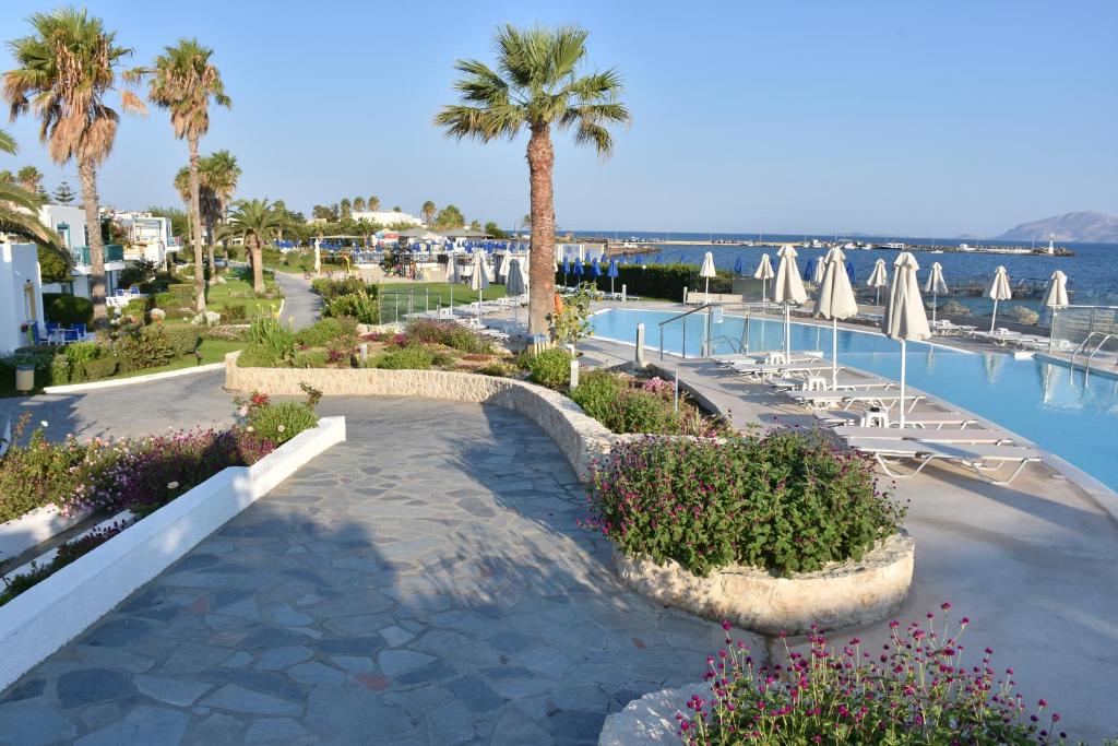 a resort with a pool and palm trees and chairs at Mastichari Bay Hotel in Mastihari