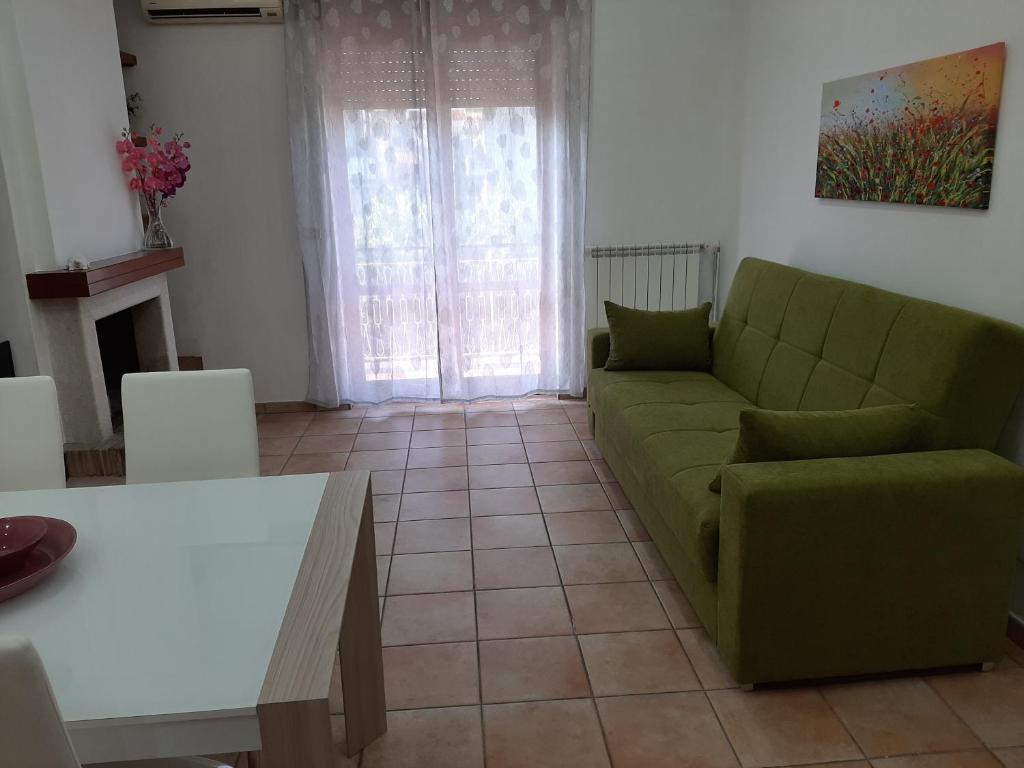 sala de estar con sofá verde y mesa en Casa Monti, en Scauri