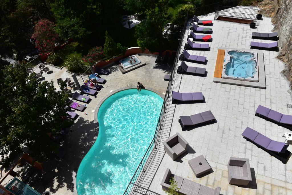 uma vista sobre uma piscina com espreguiçadeiras e cadeiras em Les Jardins De La Glacière em Corte