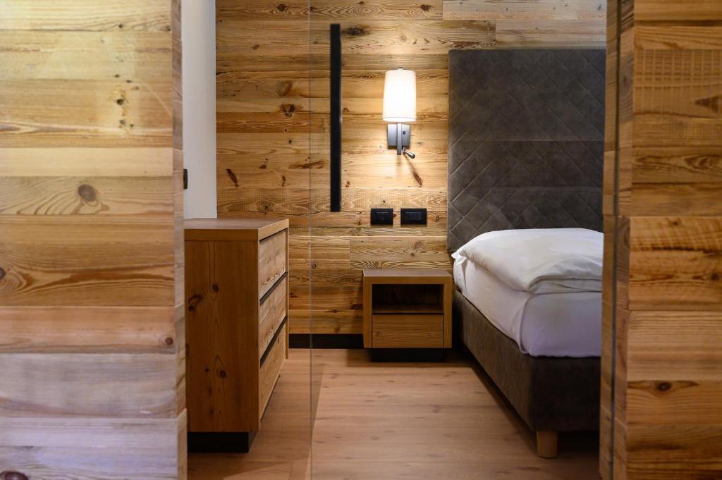 a bedroom with a bed and a wooden wall at Hotel Crozzon in Madonna di Campiglio