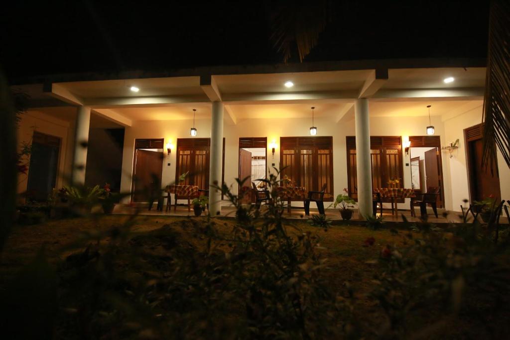 a building with chairs and tables at night at Surf Orchid Villa in Weligama
