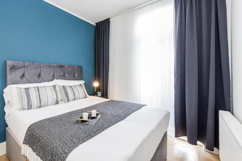 um quarto com uma grande cama branca com paredes azuis em 2 Bedrooms Serviced Apartment ExCel Exhibition Centre, O2 Arena, Stratford Olympic City, Forest Gate, Central London em Londres