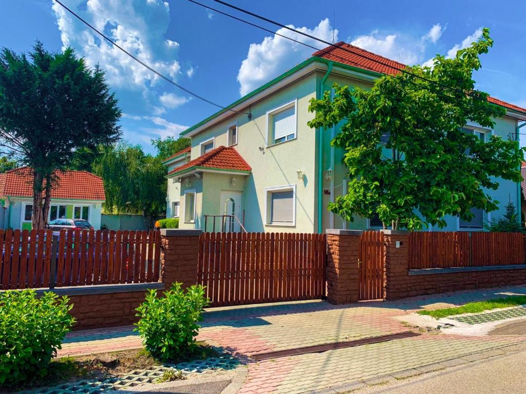 una casa con una recinzione di legno di fronte ad essa di Airport Jazmin Guesthouse a Vecsés