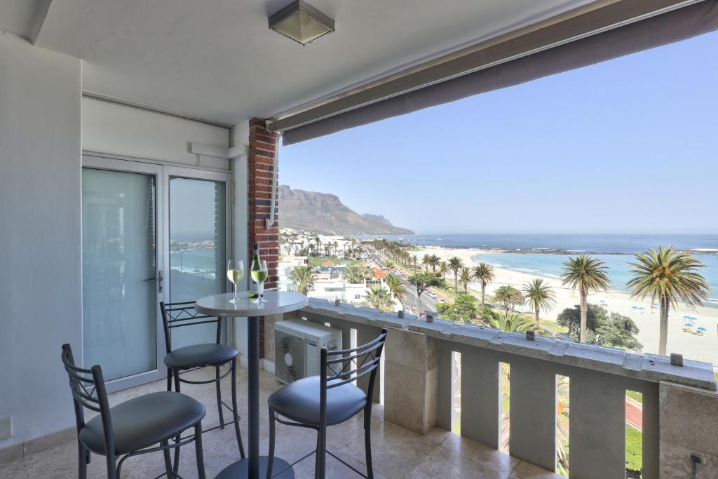 a balcony with a table and chairs and a view of the beach at Cloud Nine by Totalstay in Cape Town