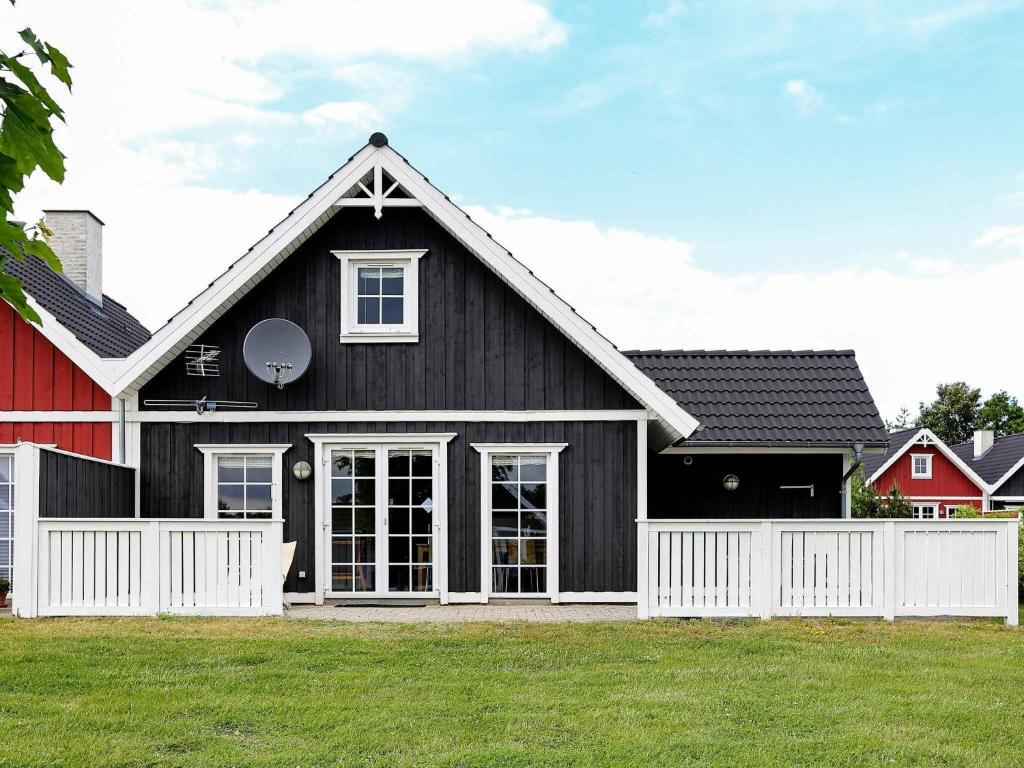 a black house with a white fence in a yard at 6 person holiday home in Vejby in Vejby