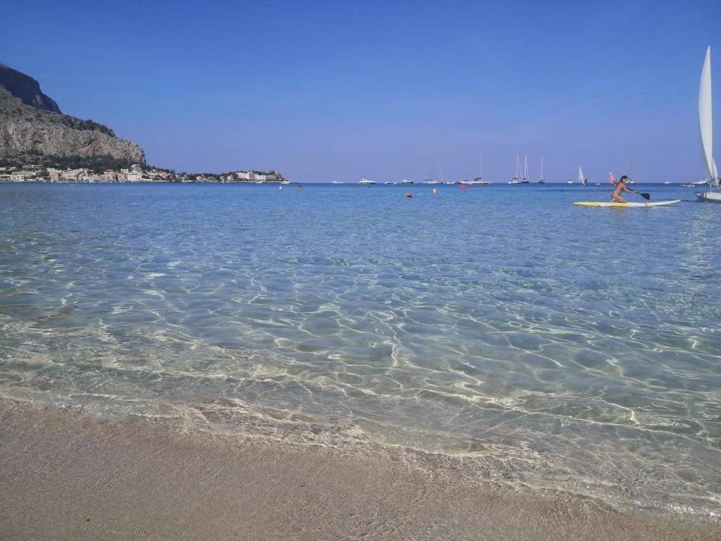 eine Person auf einem Surfbrett im Wasser am Strand in der Unterkunft VILLA LEA in Mondello