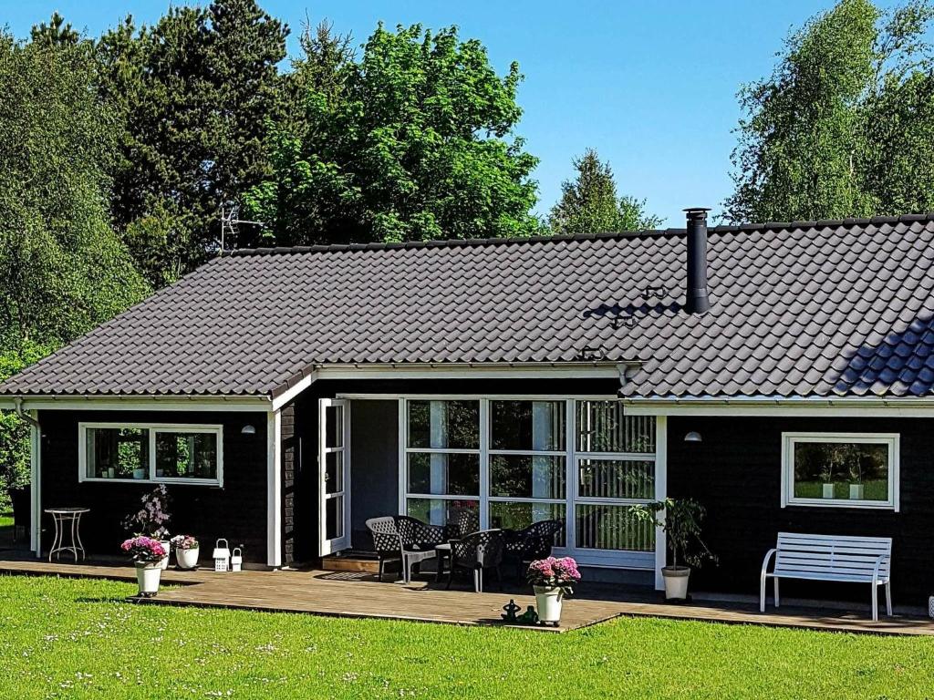 トランにあるThree-Bedroom Holiday home in Løgstør 6の玄関とベンチのある黒い家