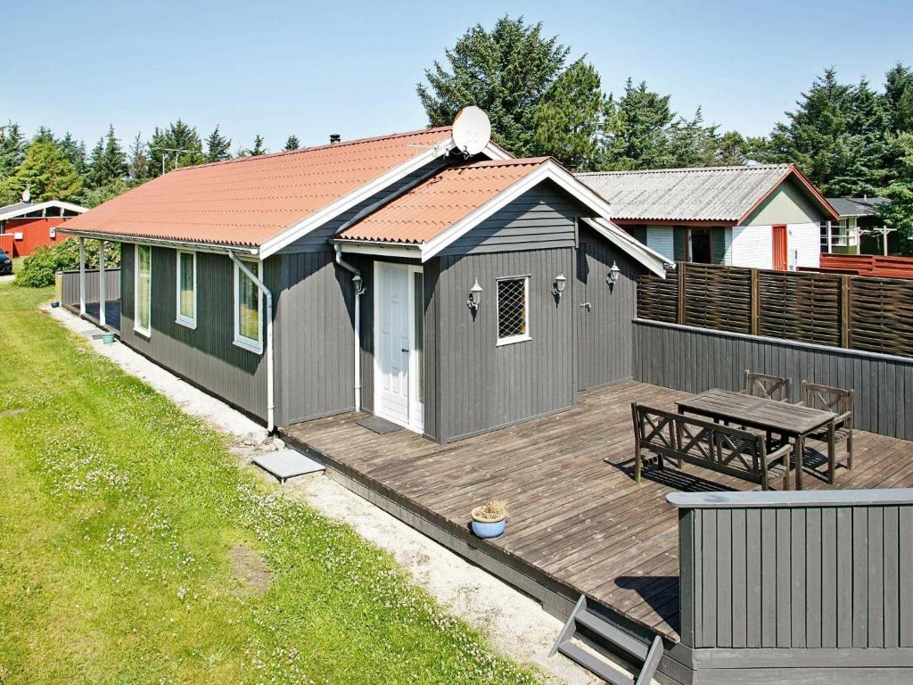 une petite maison avec une terrasse et une table de pique-nique dans l'établissement Three-Bedroom Holiday home in Løkken 41, à Grønhøj