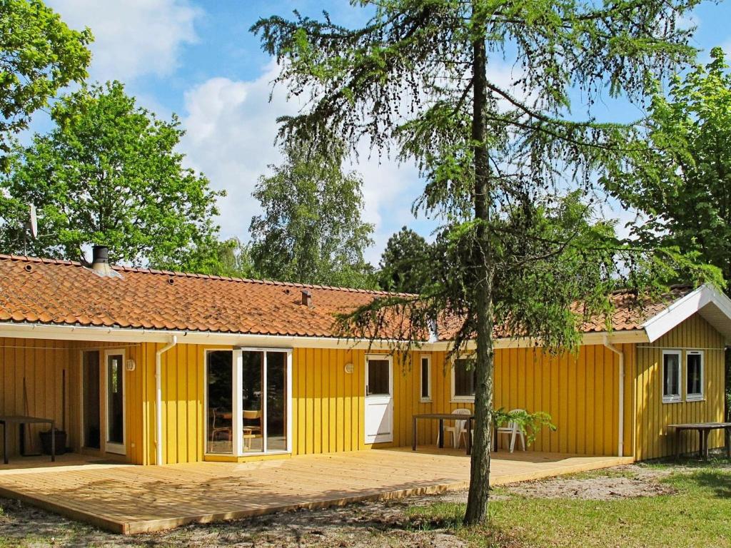 a yellow building with a patio in front of it at Four-Bedroom Holiday home in Væggerløse 18 in Marielyst