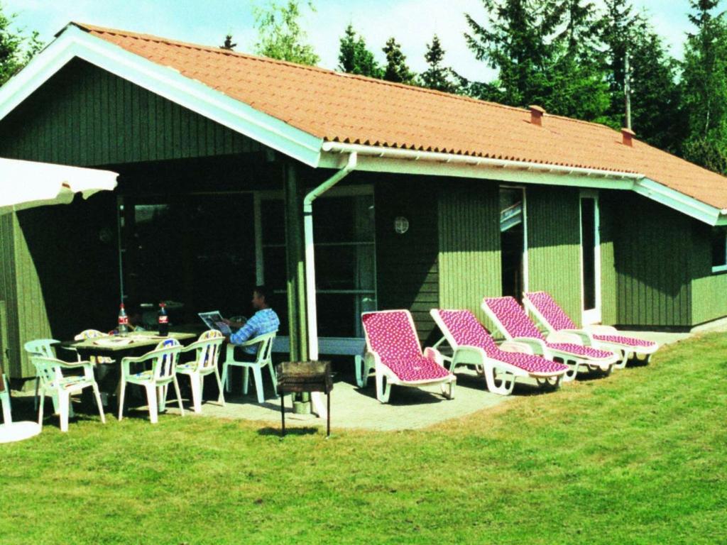 een persoon aan een tafel op een patio bij Four-Bedroom Holiday home in Væggerløse 19 in Bøtø By