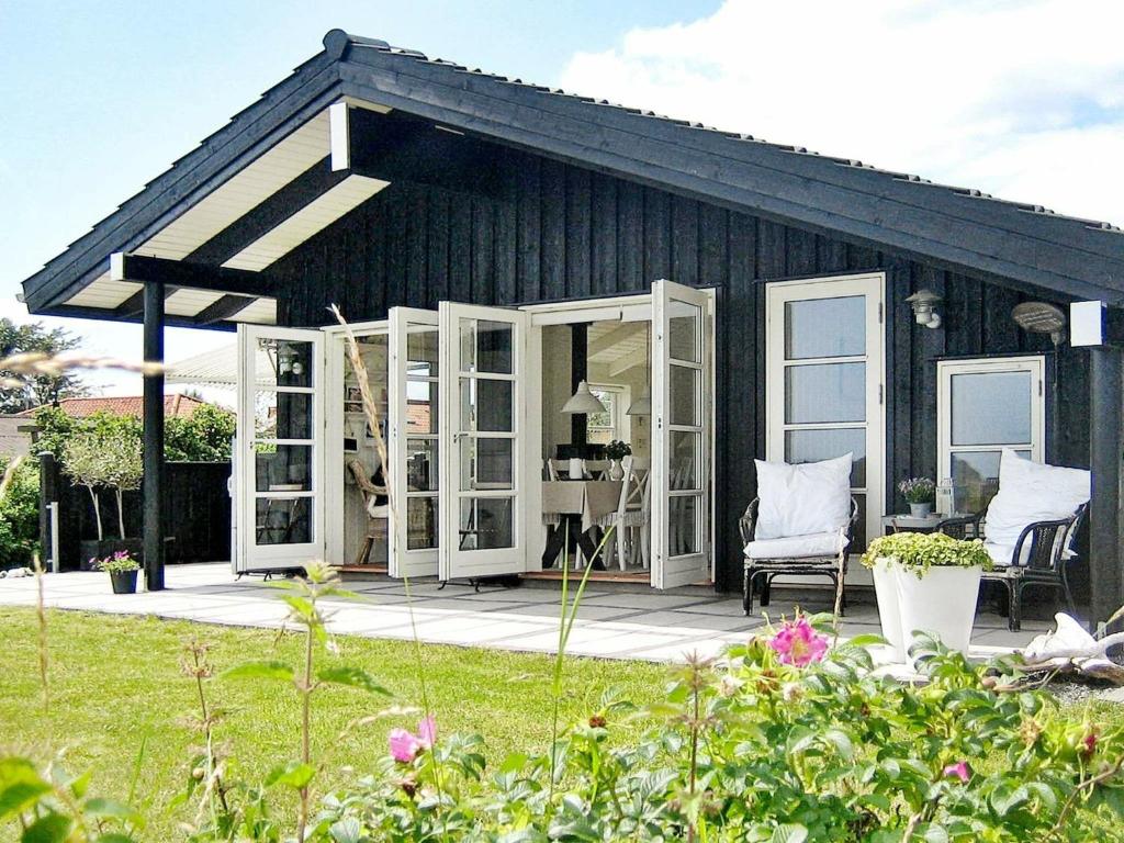 BroagerにあるThree-Bedroom Holiday home in Broager 4の白いドアとパティオのある黒い家