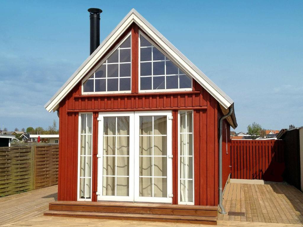 a red house with windows on a wooden deck at 4 person holiday home in Karreb ksminde in Karrebæksminde