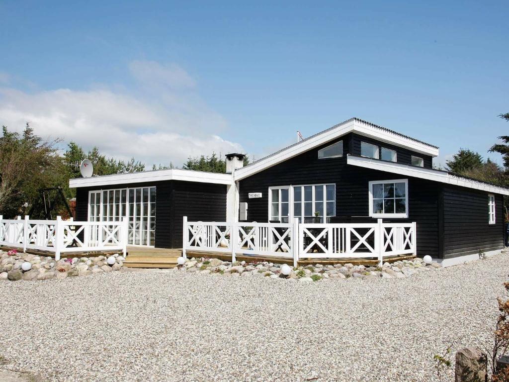 una casa negra con una cerca blanca delante de ella en 8 person holiday home in L gst r, en Trend