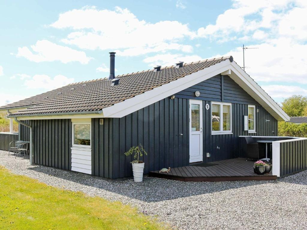 a black shed with a porch and a deck at 6 person holiday home in Hadsund in Øster Hurup