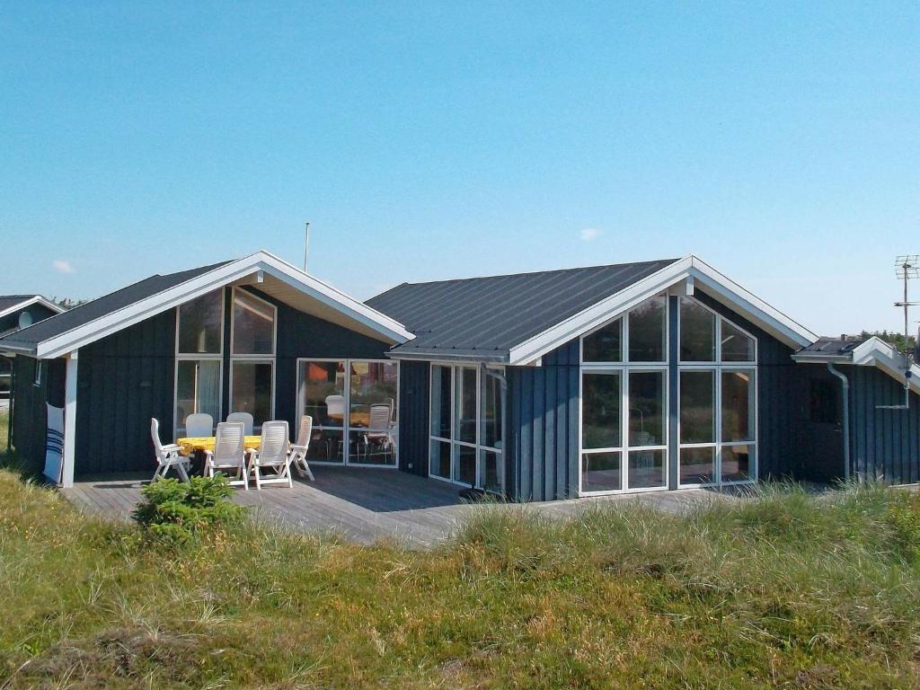 a blue house with a table and chairs on a deck at 10 person holiday home in Harbo re in Harboør