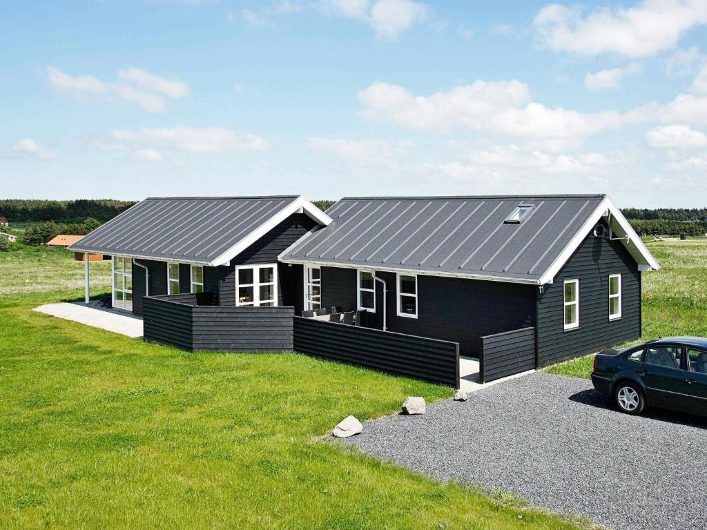 ロッケンにあるThree-Bedroom Holiday home in Løkken 40の車が目の前に停まった黒い家