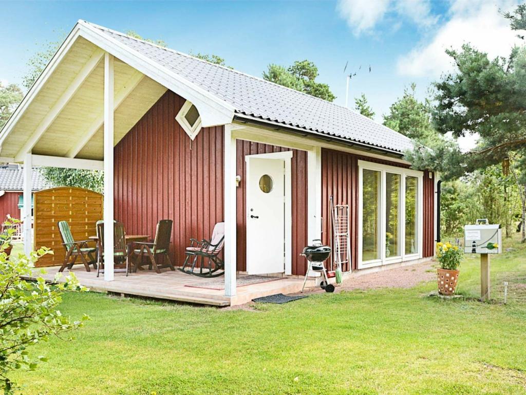 een rood huis met een veranda en een terras bij 4 person holiday home in M nster s in Mönsterås