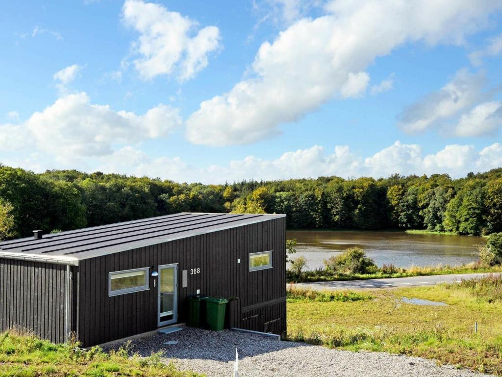 オーベンローにある8 person holiday home in Aabenraaの川の横の小さな黒い建物