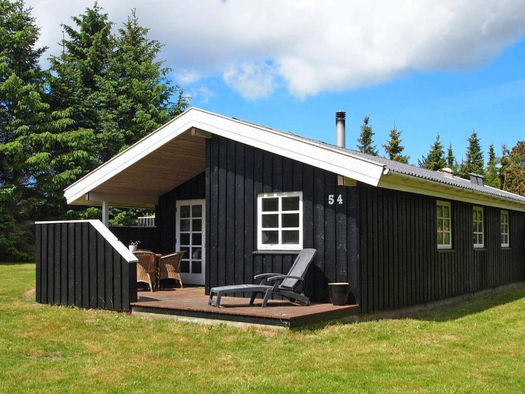 a black building with a chair on a deck at 6 person holiday home in Blokhus in Blokhus