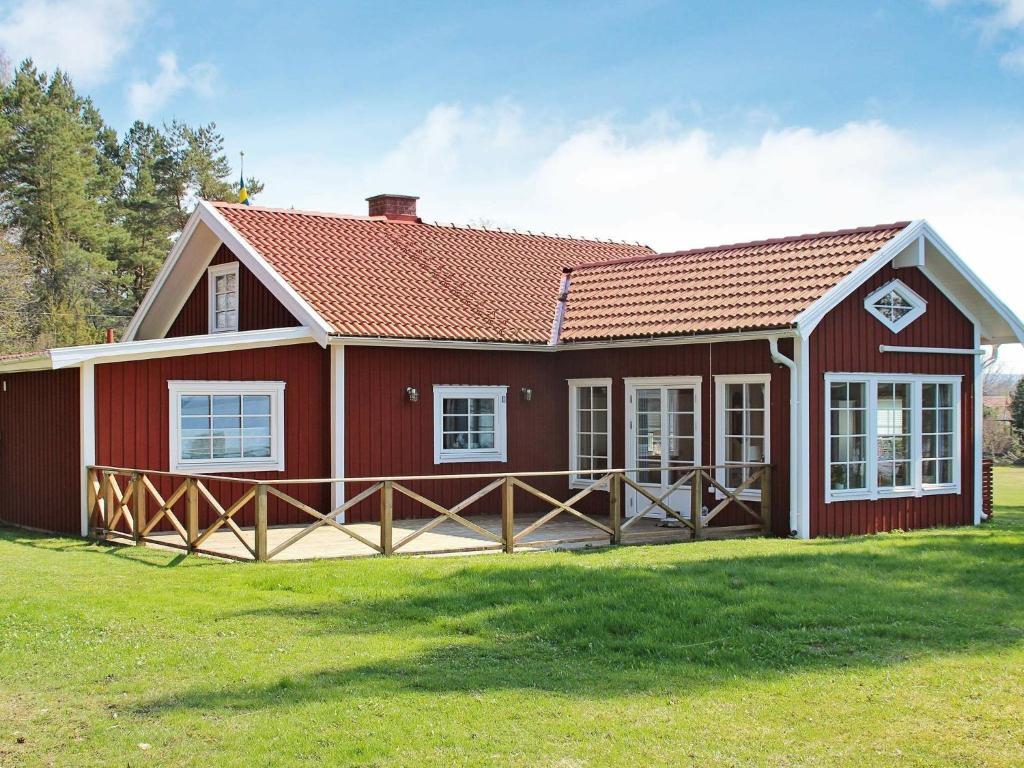 a red house with a red roof on a grass field at 5 person holiday home in MARIESTAD in Lugnås