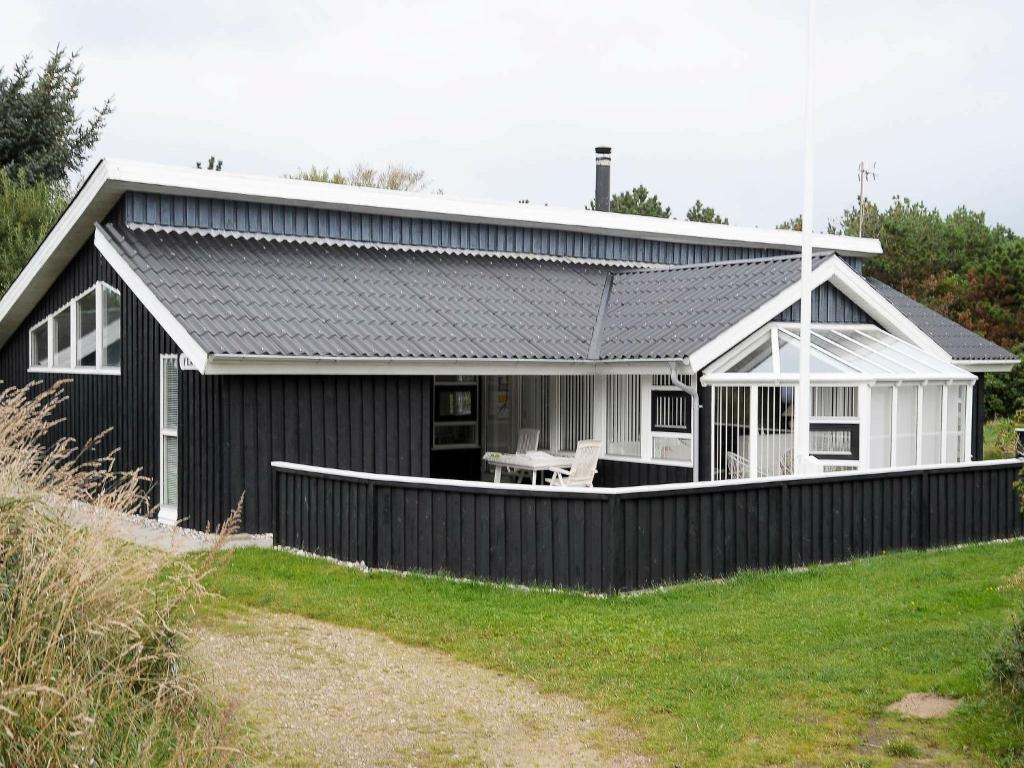 una casa en blanco y negro con una valla en Four-Bedroom Holiday home in Vejers Strand 11, en Vejers Strand