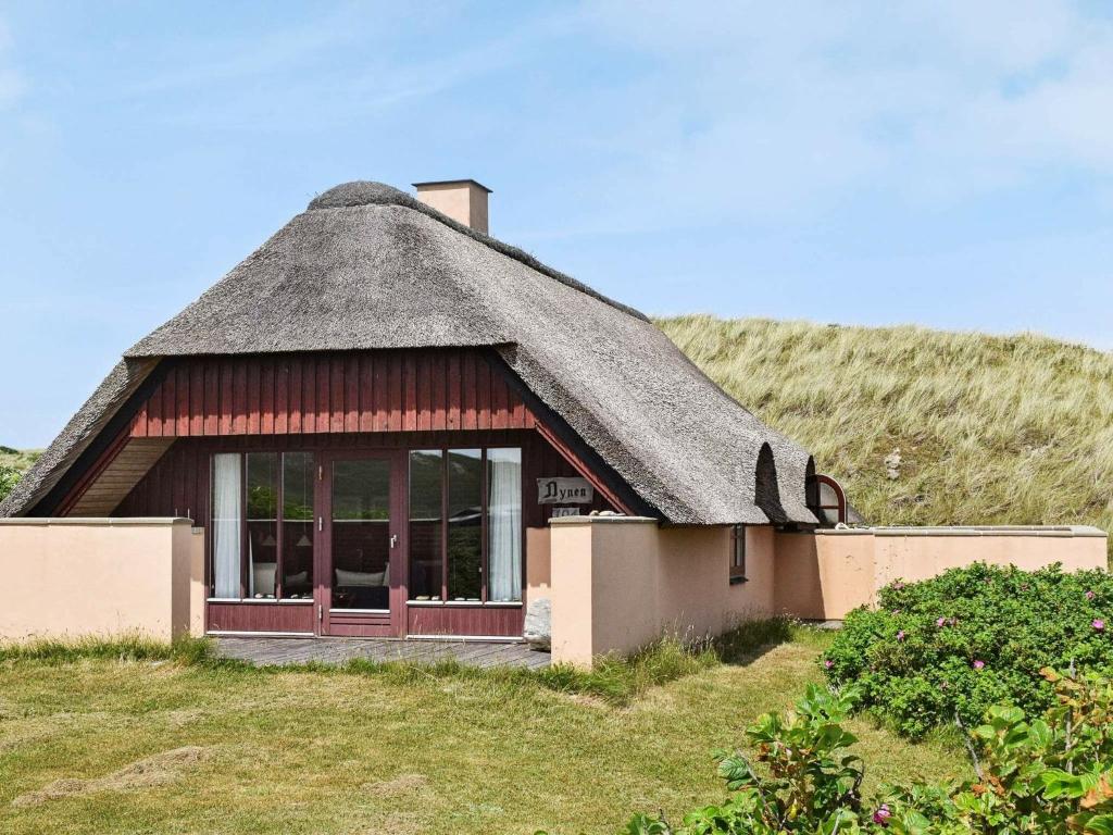 eine Hütte mit einem Strohdach auf einem Hügel in der Unterkunft Holiday home Hvide Sande VIII in Havrvig
