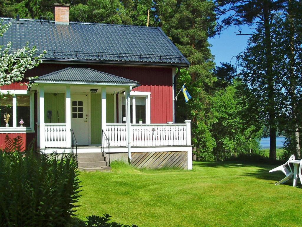 ein rotweißes Haus mit einer Veranda und einem Hof in der Unterkunft 5 person holiday home in ARVIKA in Arvika