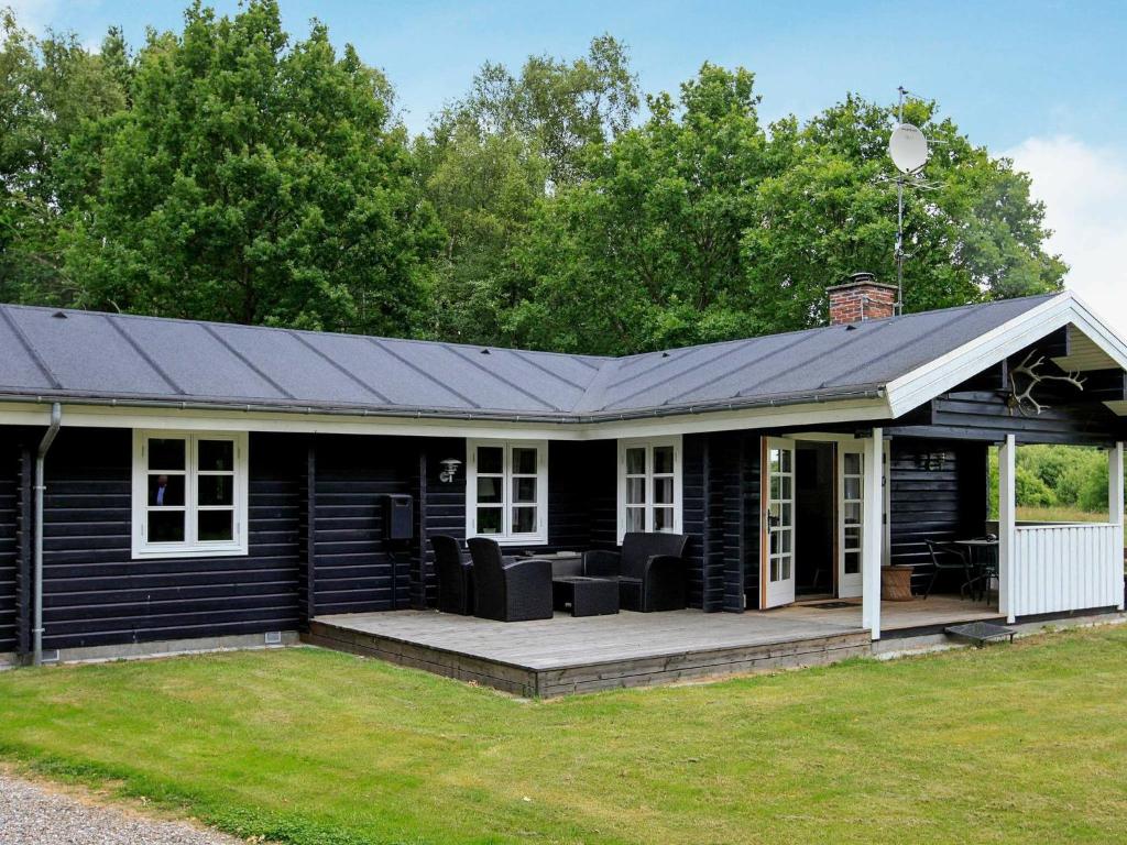 a black house with a porch and a deck at 6 person holiday home in L s in Læsø