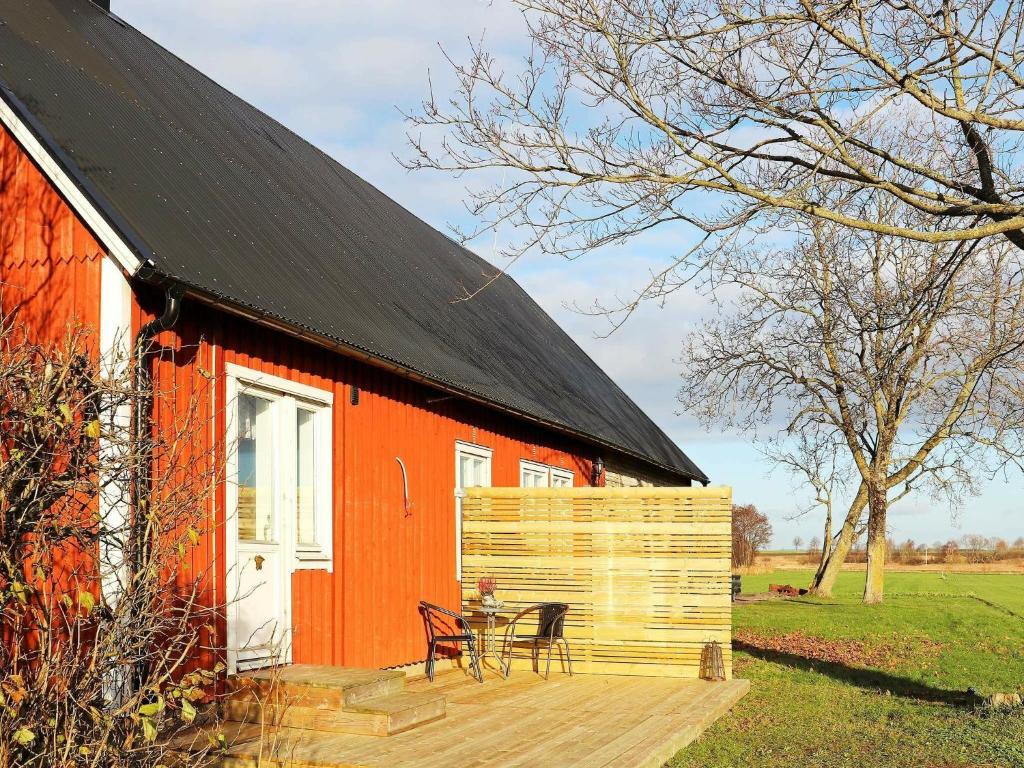 a red barn with a table and chairs on a deck at Apartment LAHOLM in Laholm