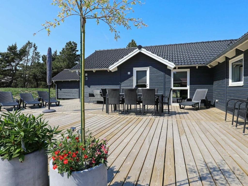 eine Terrasse mit Stühlen, einem Tisch und einem Haus in der Unterkunft Holiday home Blåvand XXVI in Blåvand