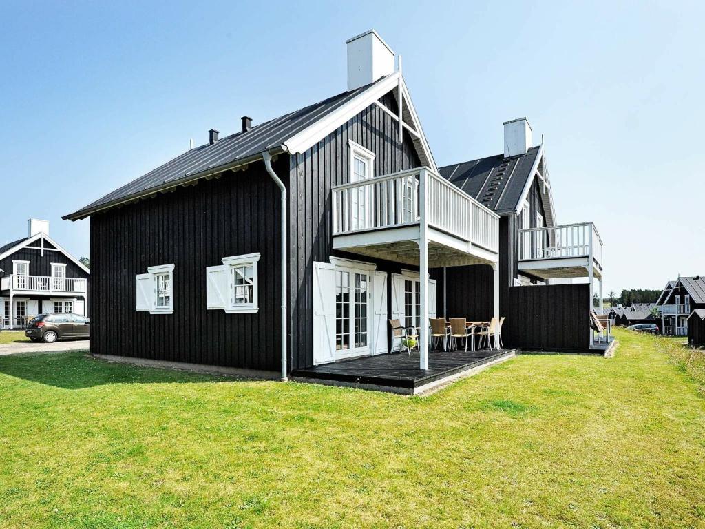 ein schwarzes Haus mit einer Terrasse auf einem Hof in der Unterkunft 8 person holiday home in Gjern in Gjern