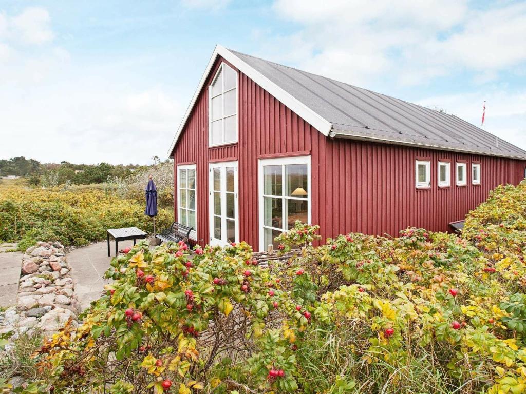 a red building with white windows and a bunch of flowers at 6 person holiday home in Store Fuglede in Store Fuglede