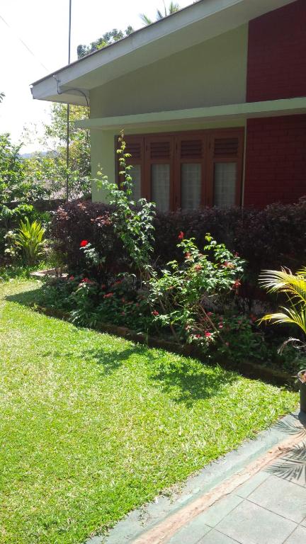 a house with a green yard with flowers and plants at Jayawimana in Kandy