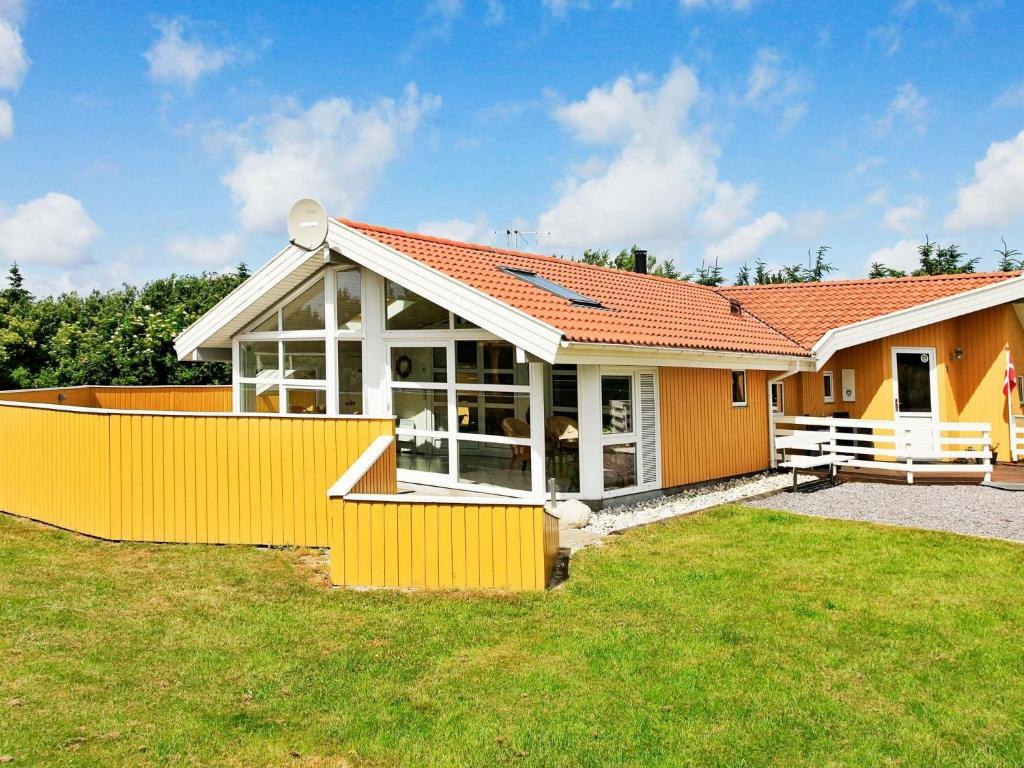 a house with an orange fence in the yard at 8 person holiday home in Vejers Strand in Vejers Strand