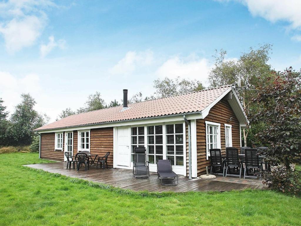 una pequeña casa con una terraza y sillas en Holiday Home Lyngstien, en Torup Strand