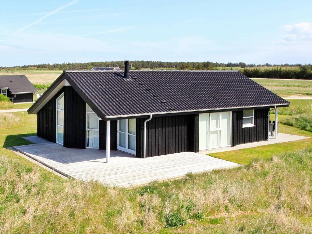 ein schwarz-weißes Haus mitten auf einem Feld in der Unterkunft 6 person holiday home in Hirtshals-By Traum in Hirtshals