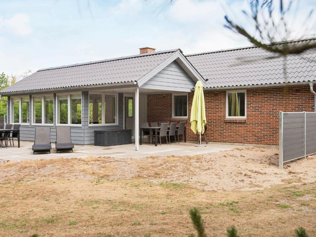 a house with a patio with a table and chairs at Holiday home Henne IX in Henne Strand