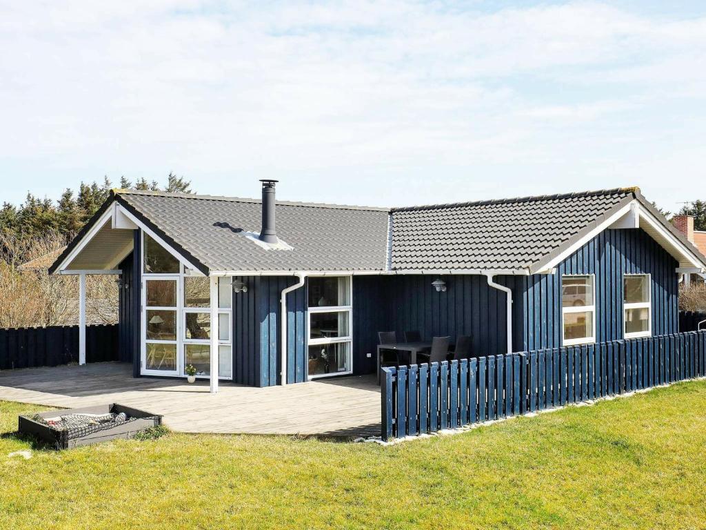 a blue house with a deck and a fence at 7 person holiday home in Thisted in Nørre Vorupør