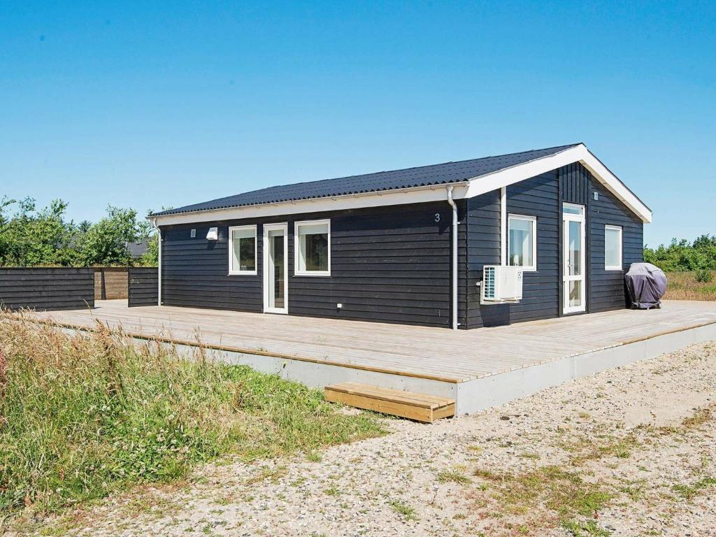 une petite maison noire avec une terrasse en bois dans l'établissement 6 person holiday home in L kken, à Løkken