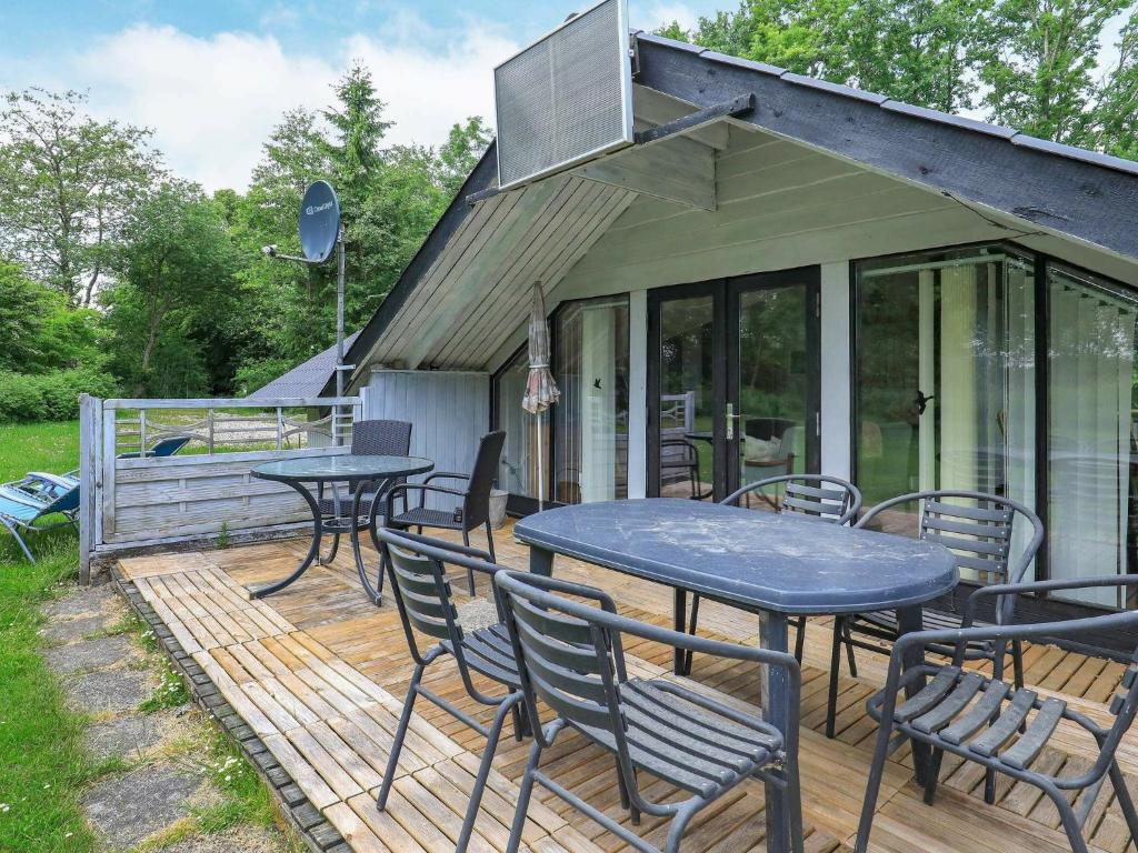 a deck with tables and chairs on a house at 6 person holiday home in Roslev in Vester Grønning