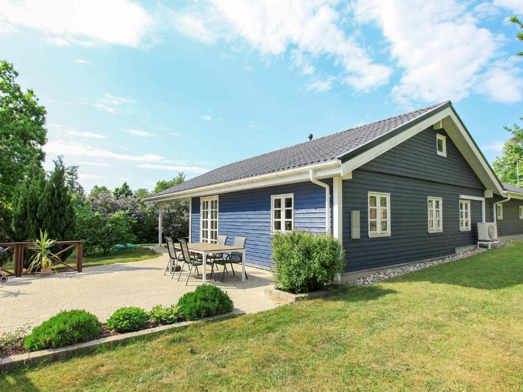 una casa azul con una mesa y sillas en un patio en 9 person holiday home in J gerspris en Jægerspris